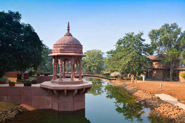 Pink sandstone pavilion reflected in a peaceful pond at Govardhan Ecovillage